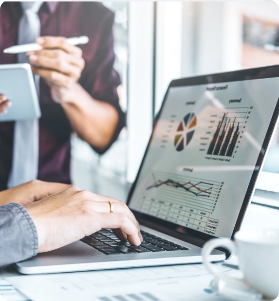 Close-up of hands working on a laptop with data analysis on the screen