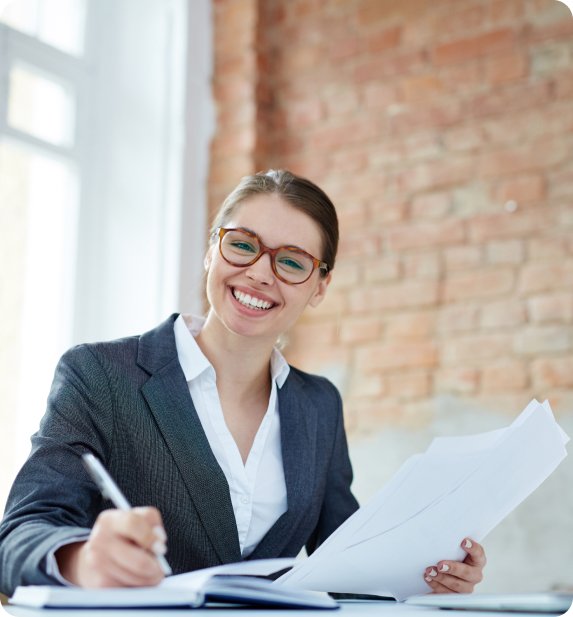 Smiling woman in a business suit reviewing documents with financial data.