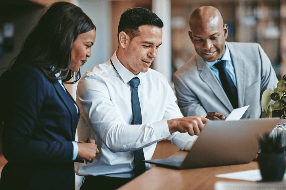 Business professionals discussing work at a laptop.