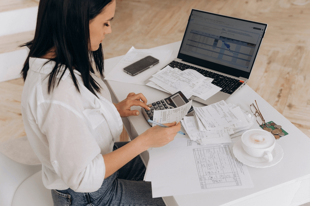 Woman doing bookkeeping with receipts and a laptop.